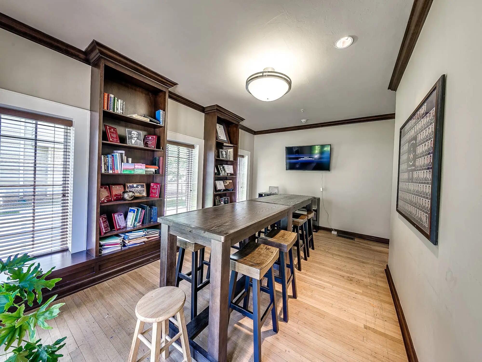 The study room, with a long high table and stools, built-in bookshelves and chapter composites on the wall